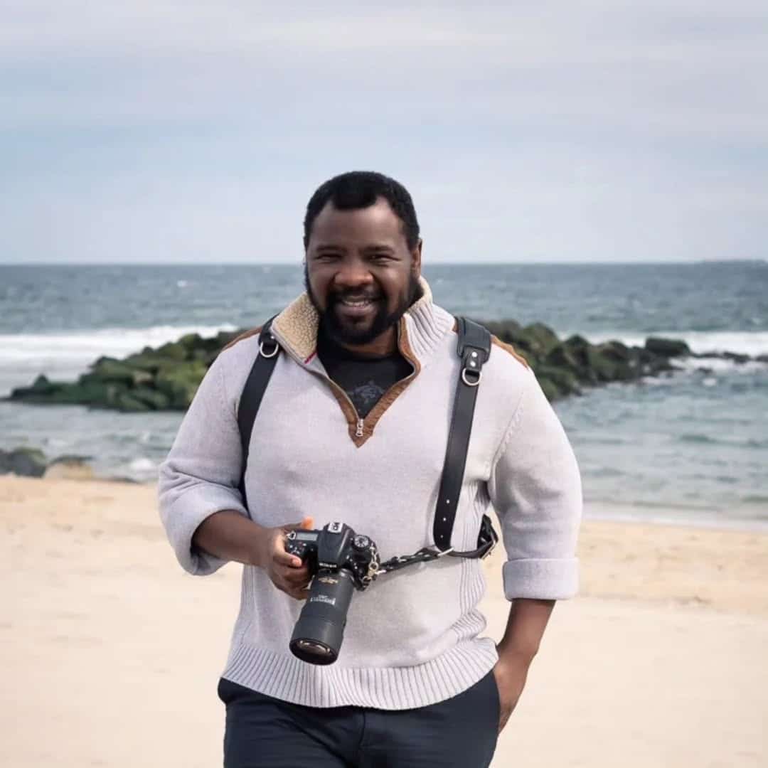 Smiling photographer holding camera on beach