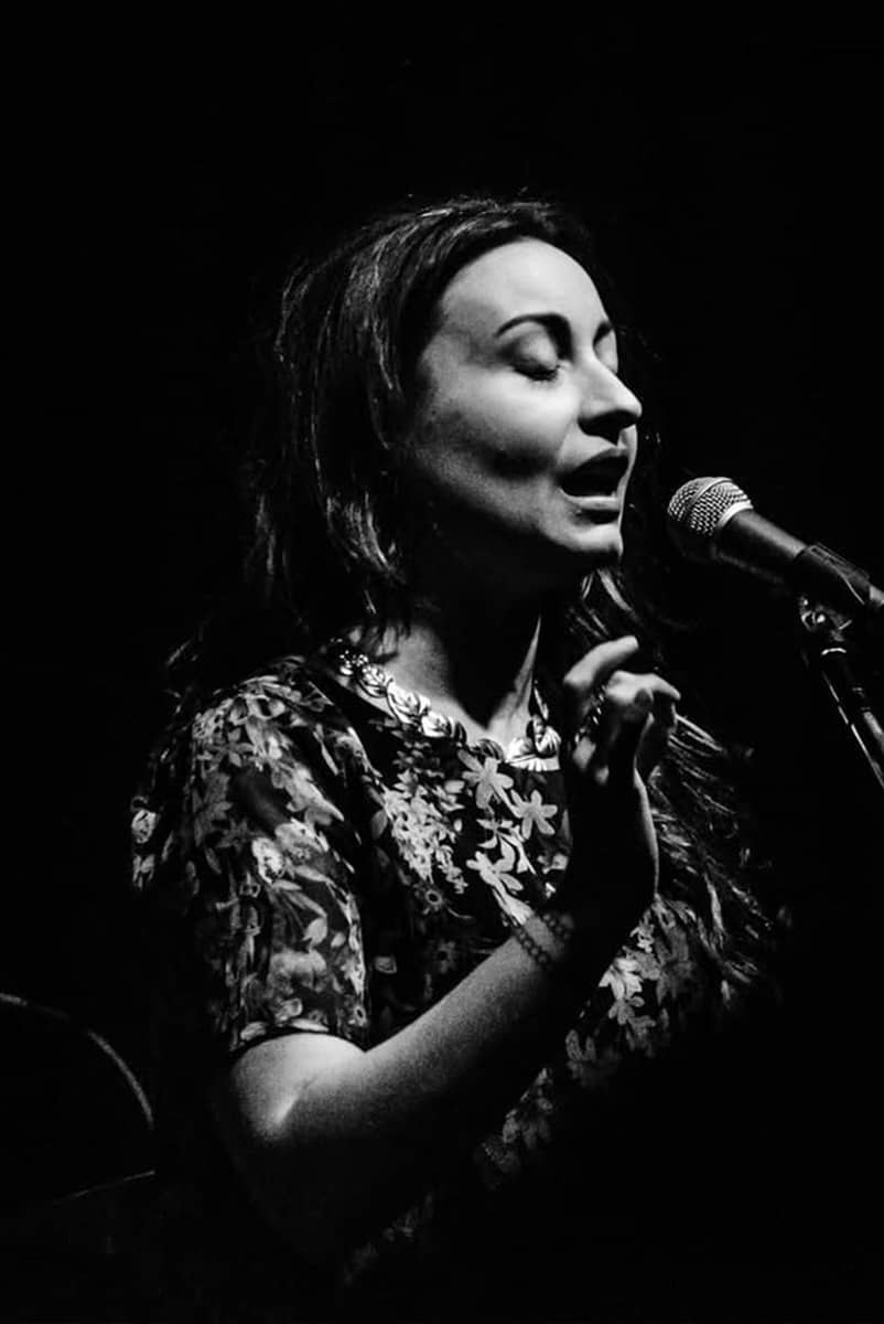 Woman singing eyes closed onstage